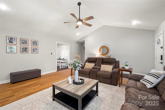living area with baseboards, a ceiling fan, light wood-style flooring, and lofted ceiling