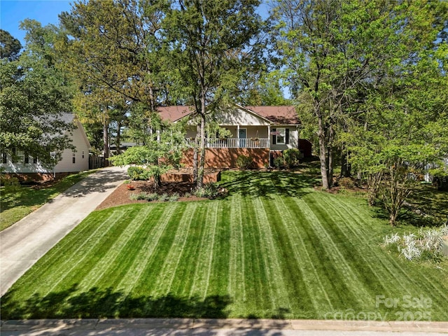 view of front facade with covered porch, driveway, and a front lawn