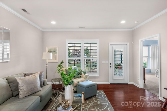 living room with baseboards, ornamental molding, wood finished floors, and visible vents