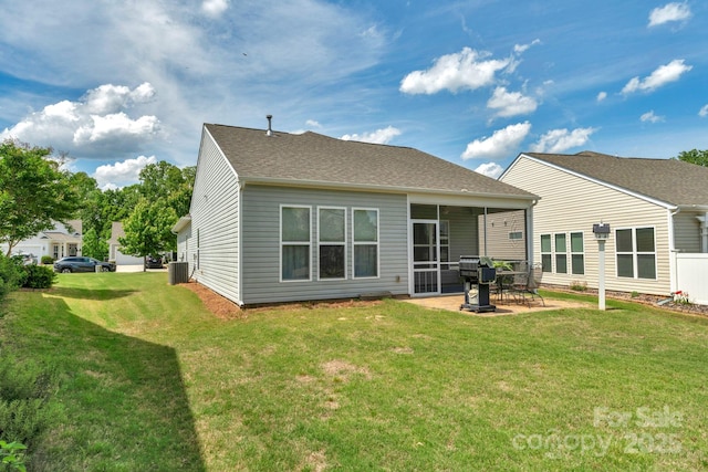 rear view of property featuring a shingled roof, a sunroom, central AC unit, a patio, and a yard