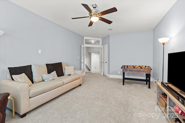 living area featuring baseboards, ceiling fan, and light carpet