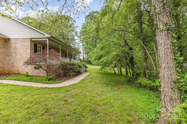 view of green lawn featuring covered porch
