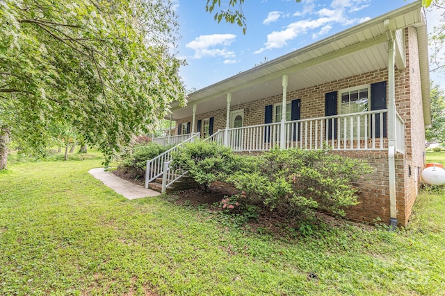 view of front of property with brick siding, a front yard, and a porch