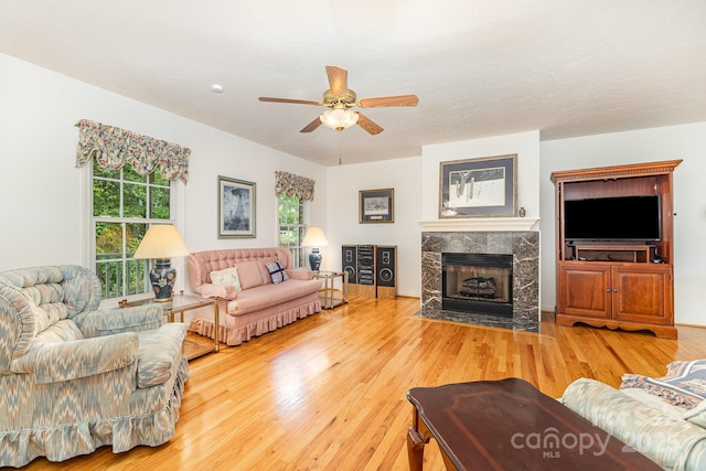 living room with ceiling fan, wood finished floors, and a high end fireplace