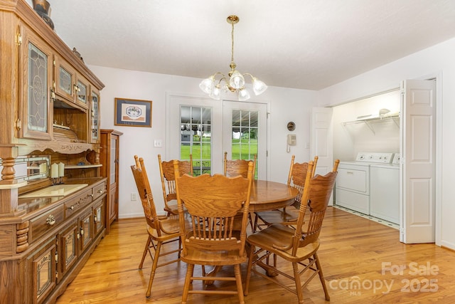 dining area with washer and clothes dryer, light wood finished floors, and a chandelier