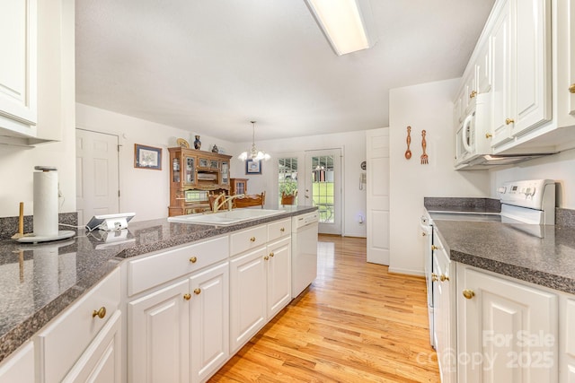 kitchen featuring white appliances, a sink, a peninsula, dark countertops, and white cabinets