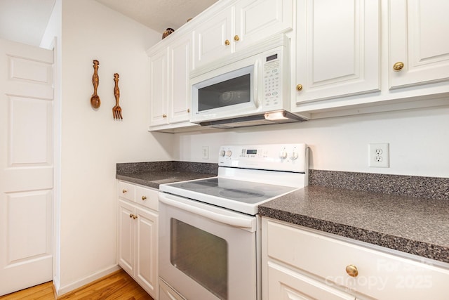 kitchen with white appliances, dark countertops, light wood finished floors, white cabinetry, and baseboards