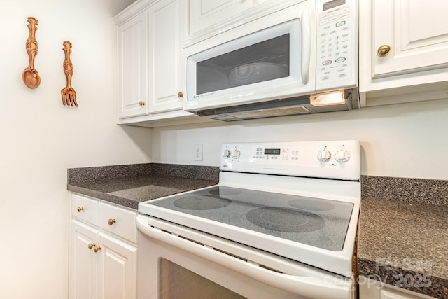 kitchen featuring white appliances, white cabinets, and dark countertops