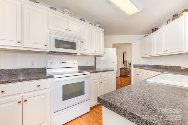 kitchen featuring white appliances, a sink, white cabinetry, and dark countertops