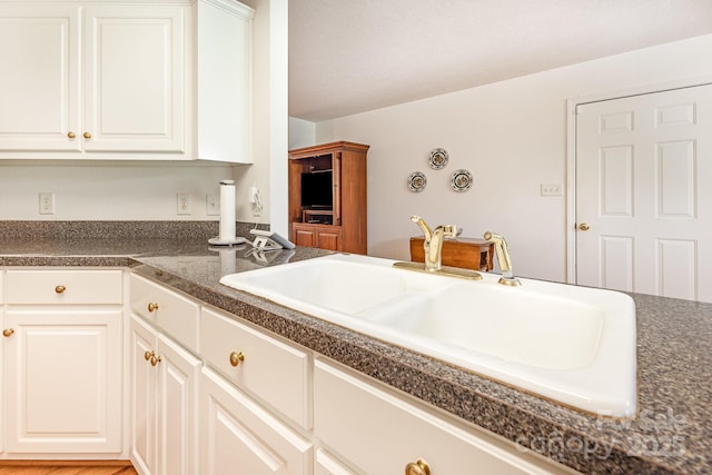 kitchen with a sink, dark countertops, and white cabinets