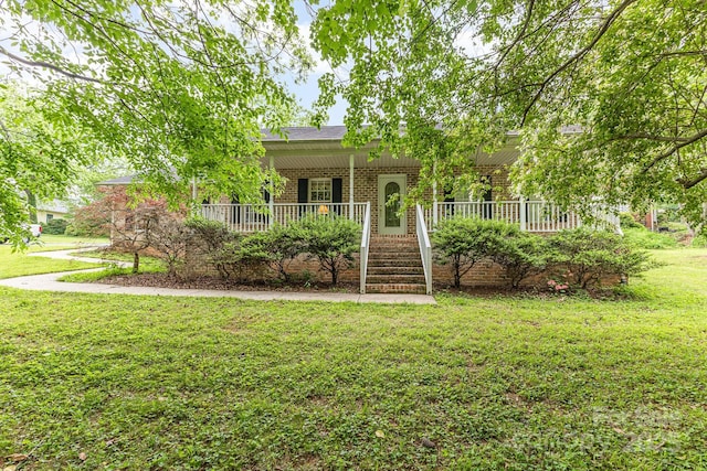 view of property hidden behind natural elements with covered porch, brick siding, and a front lawn