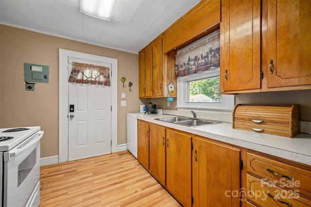 kitchen featuring brown cabinetry, light wood-style floors, light countertops, white range with electric stovetop, and a sink