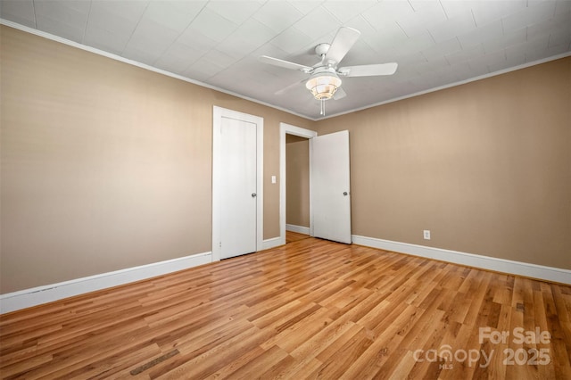 spare room featuring crown molding, a ceiling fan, light wood-style flooring, and baseboards
