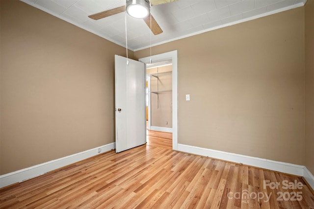 empty room with crown molding, a ceiling fan, baseboards, and light wood finished floors