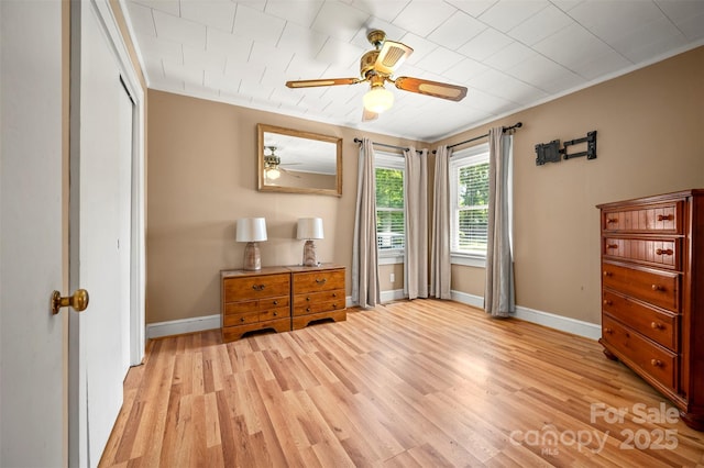 bedroom featuring a ceiling fan, baseboards, ornamental molding, and light wood-style flooring