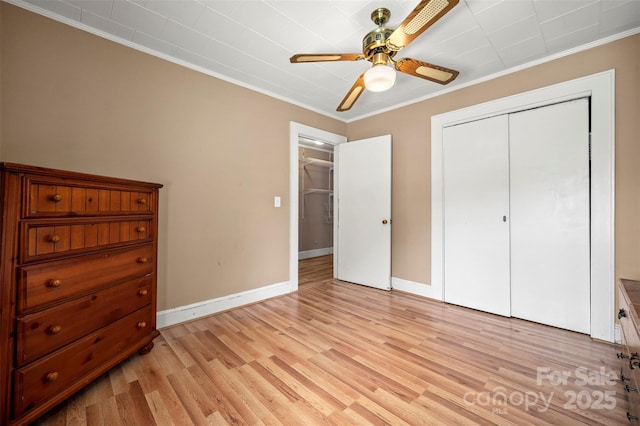 bedroom featuring baseboards, ornamental molding, light wood-style flooring, and a closet