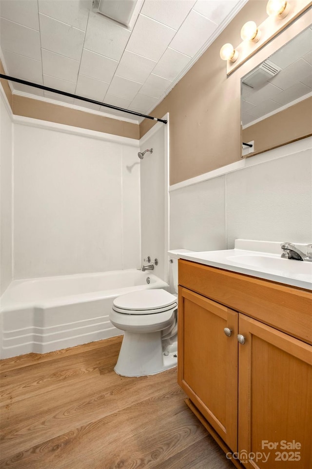 bathroom featuring vanity, wood finished floors, toilet, and shower / washtub combination