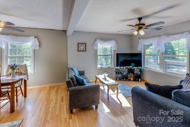 living area featuring a ceiling fan, a textured ceiling, plenty of natural light, and light wood-type flooring
