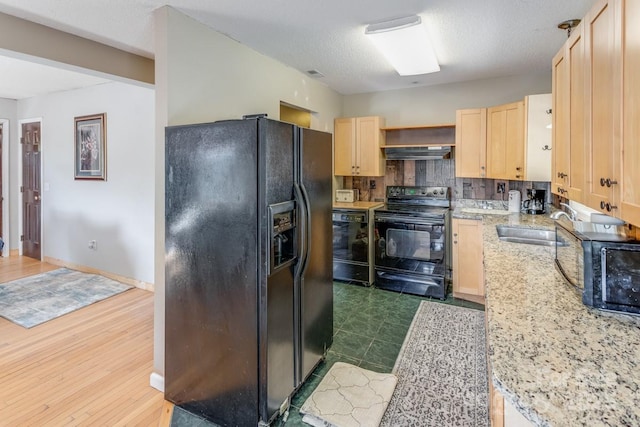 kitchen featuring decorative backsplash, light brown cabinetry, a sink, black appliances, and under cabinet range hood