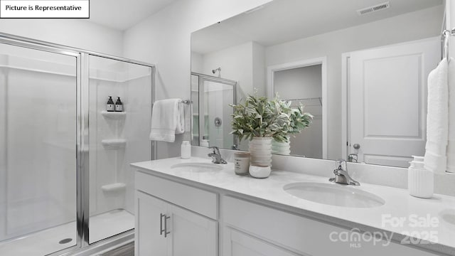 bathroom featuring a sink, a stall shower, double vanity, and visible vents