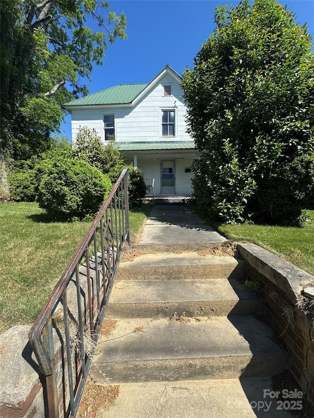 view of front of home with a front lawn, covered porch, and metal roof