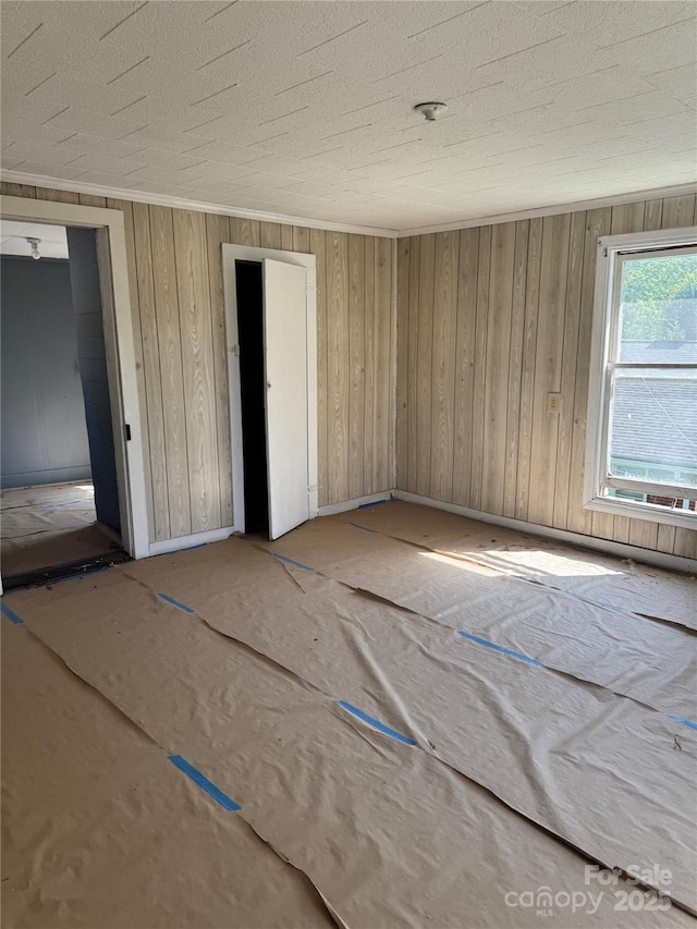 spare room with baseboards, wood walls, and a textured ceiling