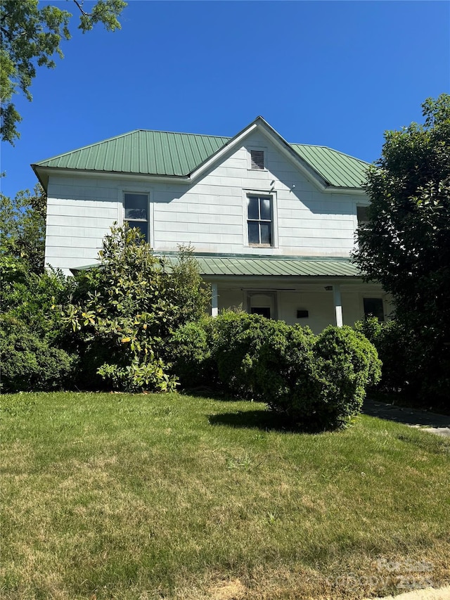 view of front of home featuring a standing seam roof, a front yard, and metal roof