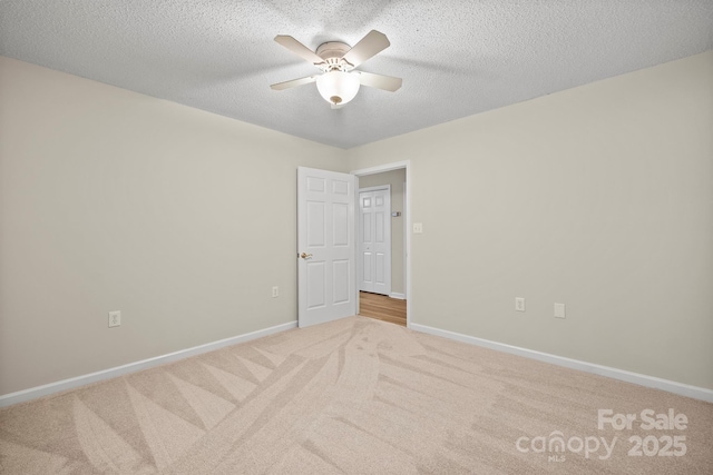 carpeted empty room featuring baseboards, a textured ceiling, and ceiling fan