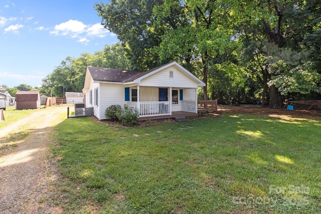 view of front of house with dirt driveway, covered porch, a front yard, and central air condition unit