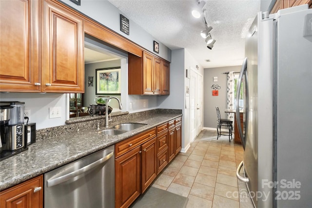 6736 Raeburn Ln, Charlotte, NC 28227 - kitchen featuring brown cabinetry, appliances with stainless steel finishes, rail lighting, a sink, and light tile patterned floors