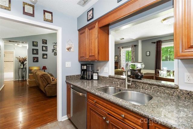 6736 Raeburn Ln, Charlotte, NC 28227 - kitchen with stainless steel dishwasher, visible vents, dark stone counters, brown cabinets, and a sink