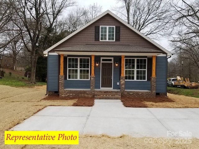 bungalow with roof with shingles, covered porch, and crawl space