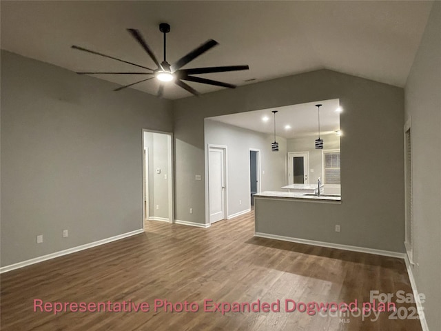 unfurnished living room featuring baseboards, dark wood-style flooring, ceiling fan, and a sink