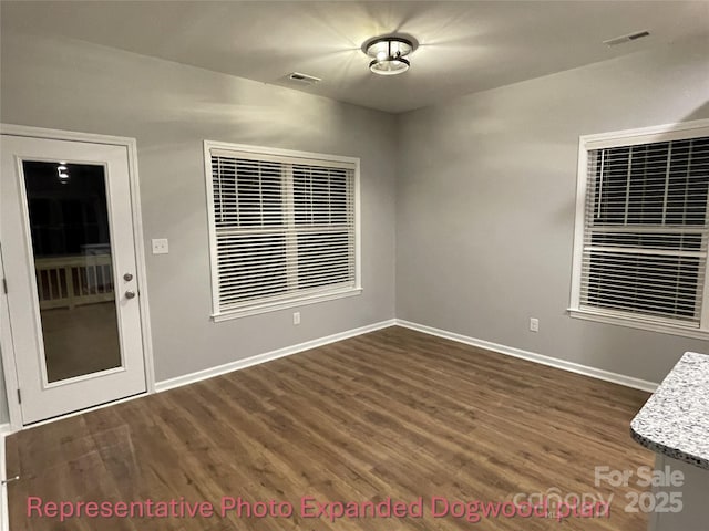 spare room featuring baseboards, wood finished floors, and visible vents
