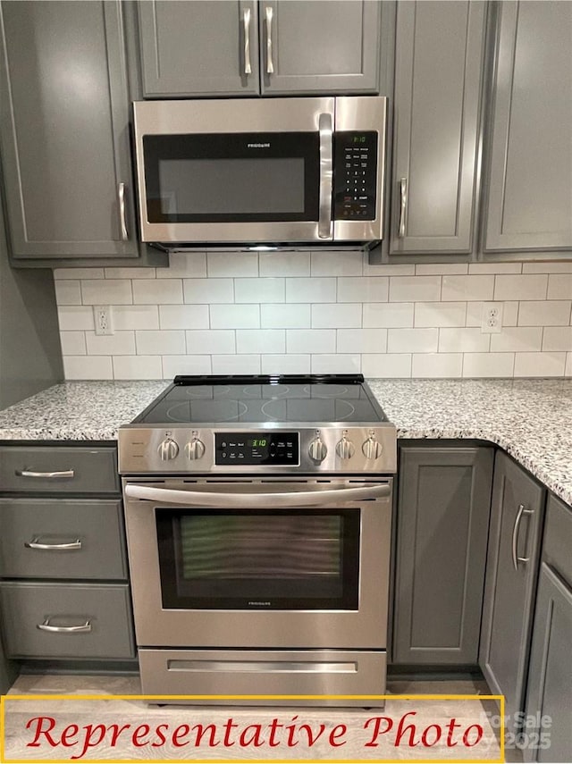 kitchen featuring backsplash, light stone countertops, and stainless steel appliances