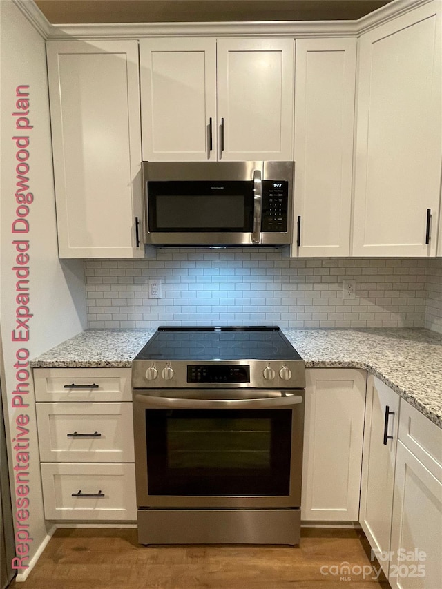 kitchen featuring light wood-style floors, appliances with stainless steel finishes, white cabinets, and decorative backsplash