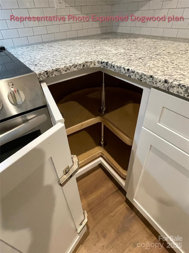 interior details with backsplash, stove, and wood finished floors