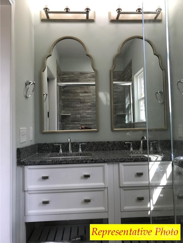 bathroom featuring a sink, a stall shower, and double vanity