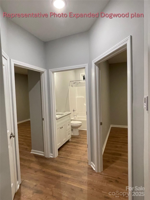 corridor featuring baseboards, dark wood finished floors, and a sink