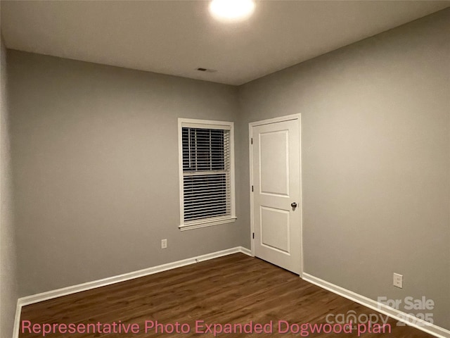 empty room with baseboards, visible vents, and dark wood-type flooring