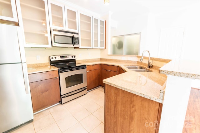 525 N Graham St Unit 3F, Charlotte, NC 28202 - kitchen with brown cabinetry, a sink, light stone counters, a peninsula, and stainless steel appliances