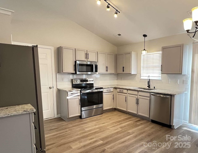kitchen featuring visible vents, tasteful backsplash, a sink, lofted ceiling, and stainless steel appliances