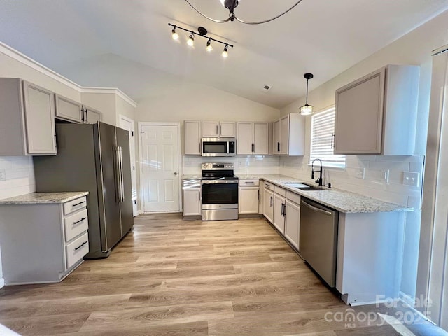 kitchen featuring light stone countertops, a sink, lofted ceiling, light wood-style floors, and stainless steel appliances