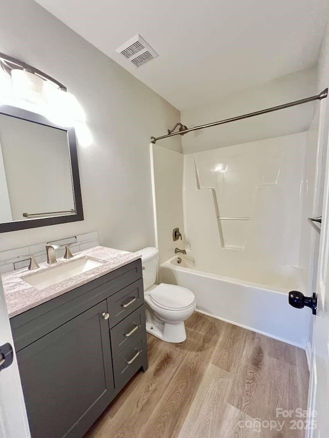 full bath featuring visible vents, shower / tub combination, wood finished floors, vanity, and toilet