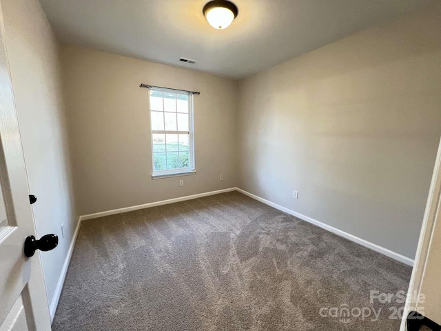 empty room featuring carpet floors, baseboards, and visible vents