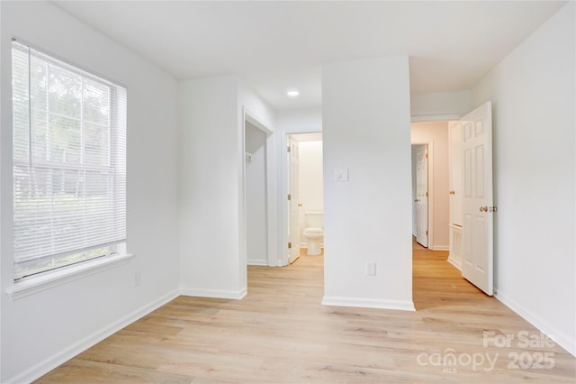 unfurnished room with baseboards, light wood finished floors, and a wealth of natural light
