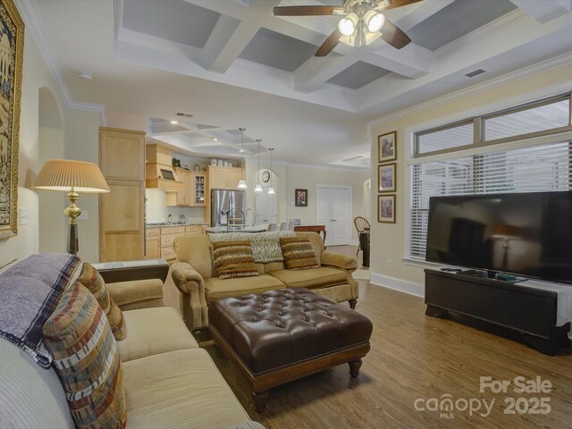 living area featuring crown molding, a ceiling fan, coffered ceiling, and dark wood finished floors