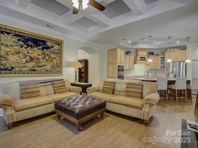 living area featuring crown molding, arched walkways, light wood-style flooring, visible vents, and coffered ceiling