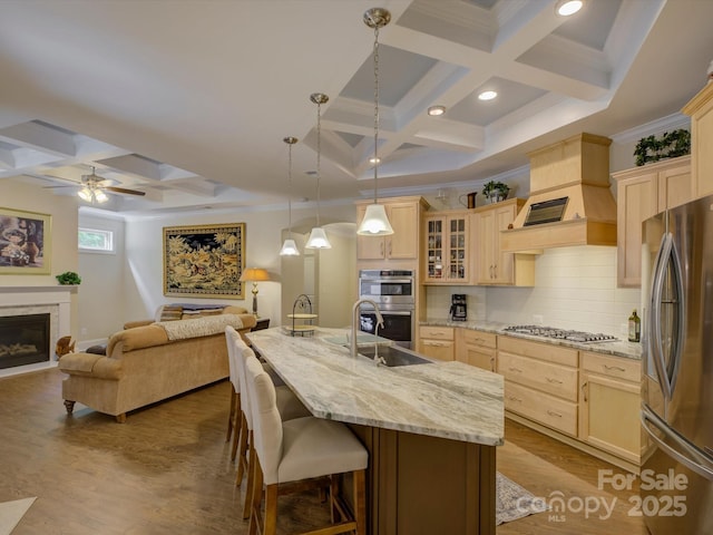kitchen with light brown cabinetry, coffered ceiling, stainless steel appliances, and open floor plan