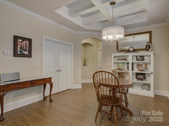 dining space with crown molding, coffered ceiling, wood finished floors, and beamed ceiling